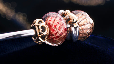 Trollbeads-Armreif mit goldenem Herz-Spacer, glitzernden Glasbeads und einer silbernen Mutterschafts-Perle mit Gold 