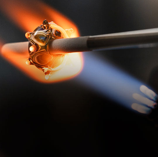Glasperle wird über einer glühenden Flamme hergestellt