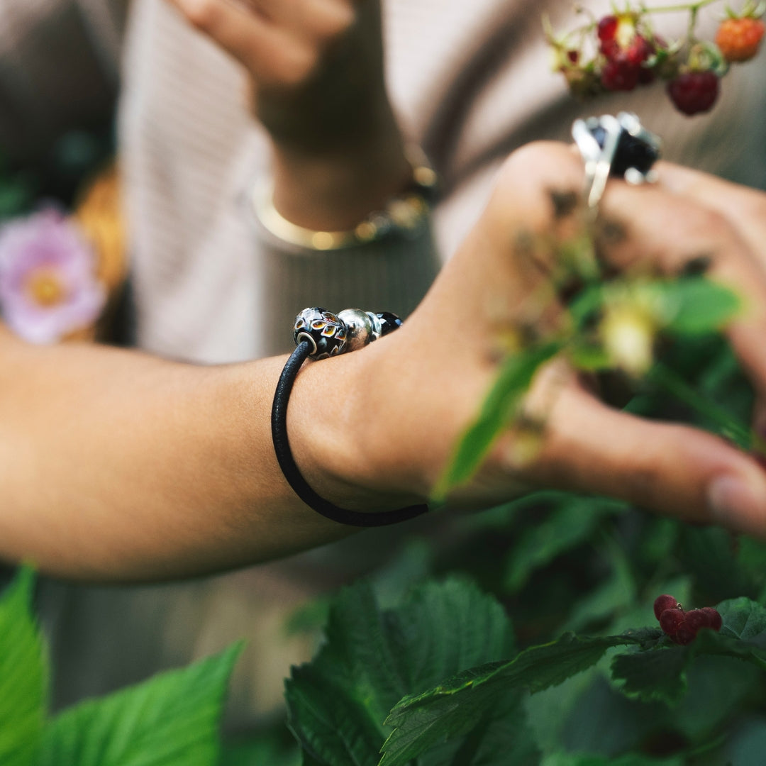 Model harvesting berries while wearing a leather bracelet with beads